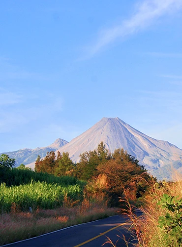 Paisaje de carretera y de fondo los volcanes de Colima